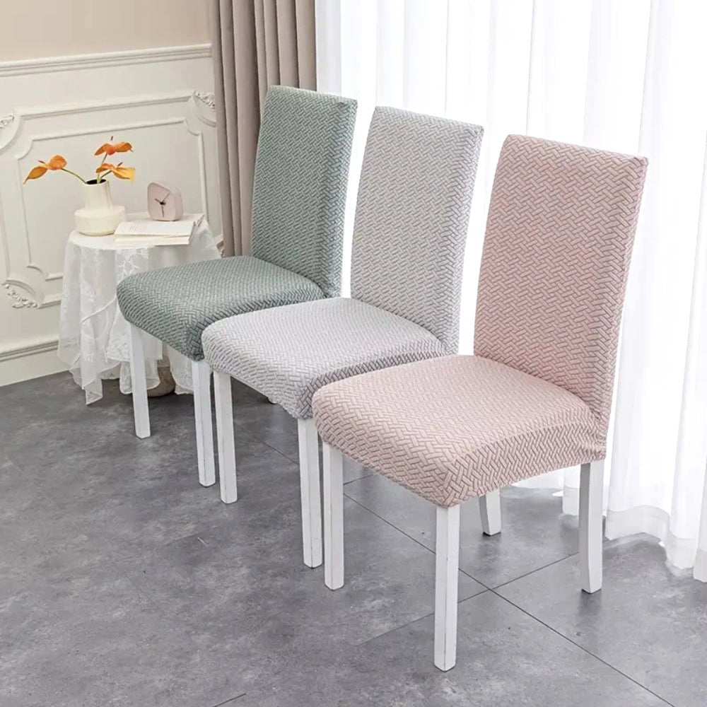 Three dining chairs showcasing Veluxe Haven Jacquard Velvet Dining Chair Covers with Stretch Fit in soft pink, soft white, and olive green. The covers feature a textured jacquard pattern and provide a snug fit.