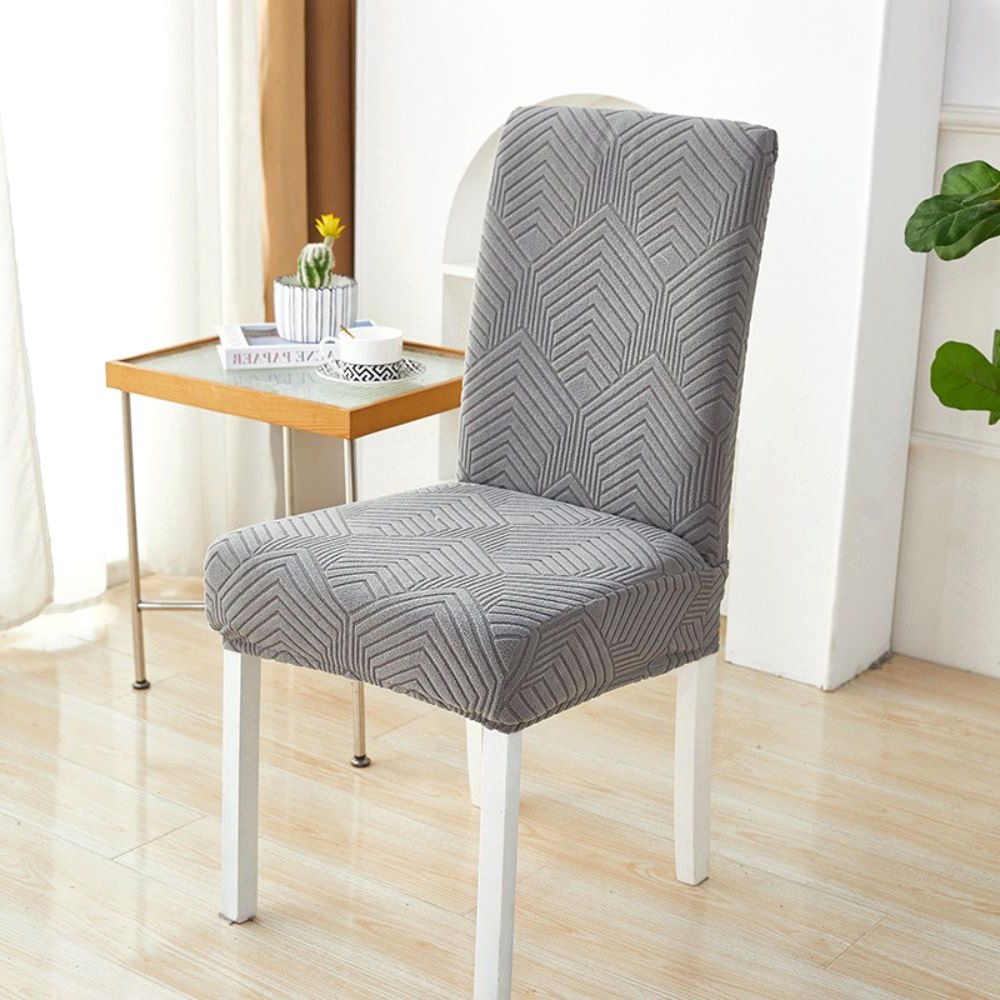 A charcoal gray Velvet Haven elastic jacquard chair cover with a Chevron Maze pattern on a white dining chair. The cover provides a stretch fit and modern design, suitable for furniture protection and home decor.