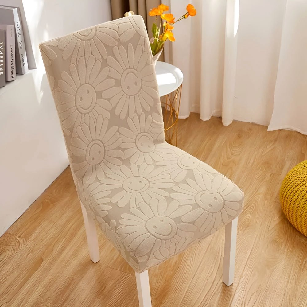 Oat Beige Blossom Aura stretch chair cover in floral fabric with elastic fit, displayed on a dining chair in a home setting.