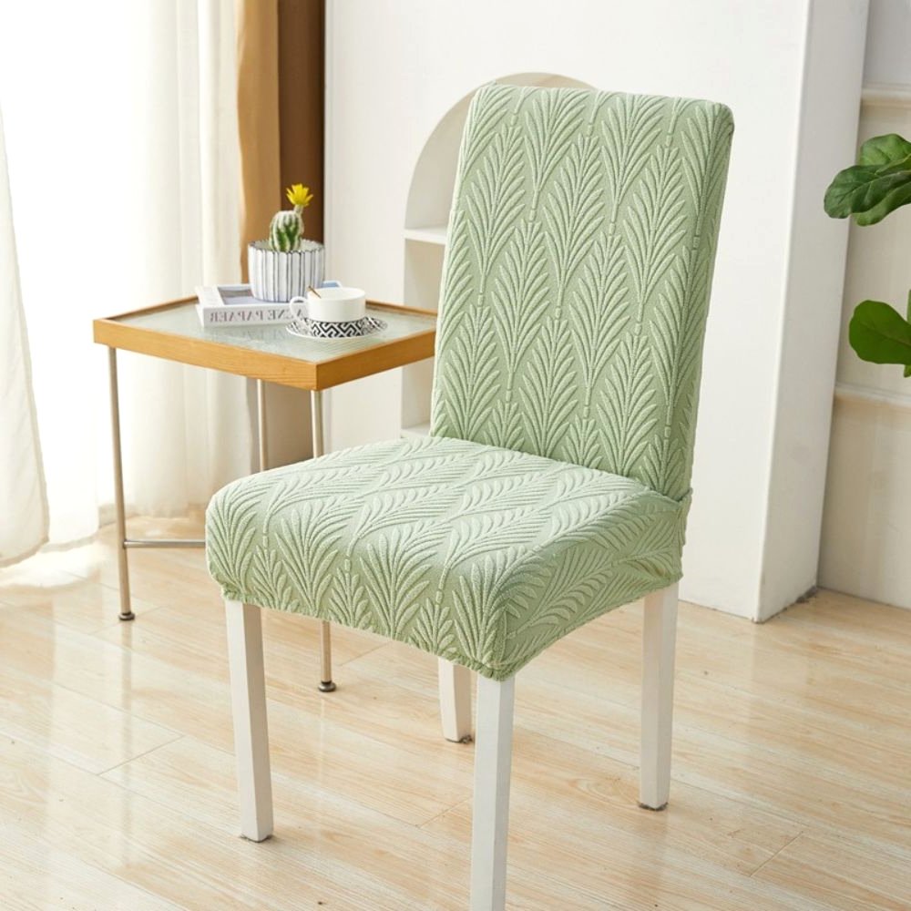 Velvet Haven Elastic Jacquard Chair Cover in Sage Green Palm Weave pattern, shown on a white dining chair. This stretch fit furniture protector offers a modern design and easy installation.
