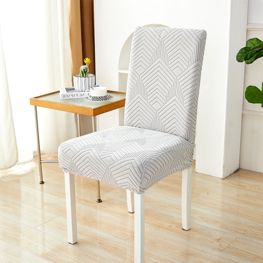 A soft white Velvet Haven elastic jacquard chair cover with a Chevron Maze pattern on a white dining chair. The cover provides a stretch fit and modern design, suitable for furniture protection and home decor.
